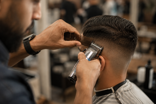 Professional barber cutting men's haircut at B & H Barber Shop